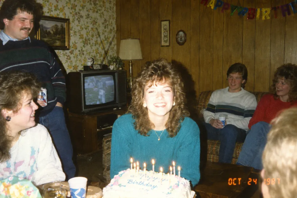 1987 living room party snapshot lit by direct on-camera flash, with a date stamp