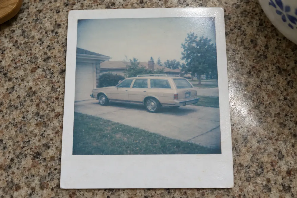 Polaroid 600 instant print from 1983 of a station wagon in a suburban driveway