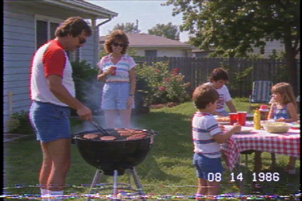 Paused VHS home video still of a 1986 backyard barbecue with a burnt-in timecode